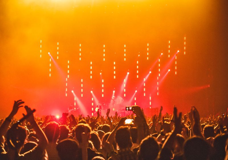 Foule levant les mains devant une scène de concert éclairée